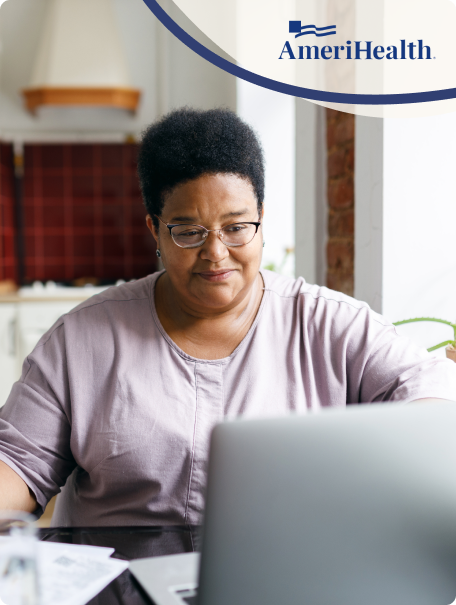 Woman with short hair and glasses looks at a laptop in her kitchen