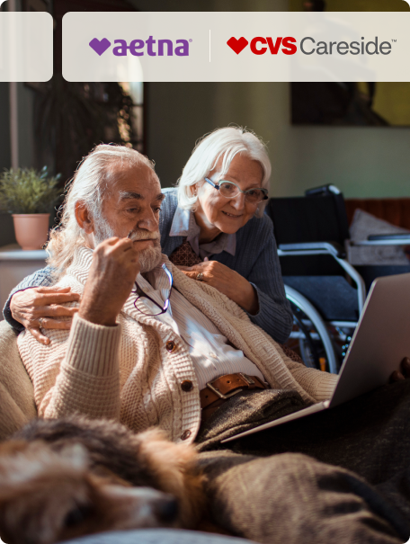 Husband and wife looking at a laptop together as the wife puts her arms around him.