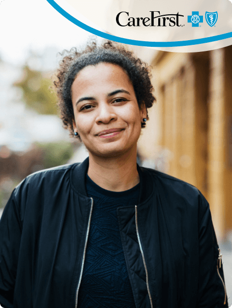 Smiling woman looking at the camera with a black jacket on and the CareFirst logo in the top right corner.
