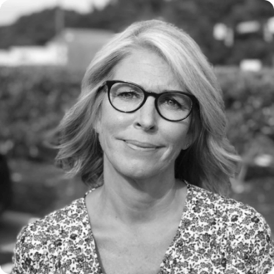 Janet Reimer wearing glasses and a floral blouse and smiling at the camera