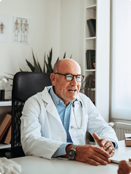 A doctor in a white coat at his desk.