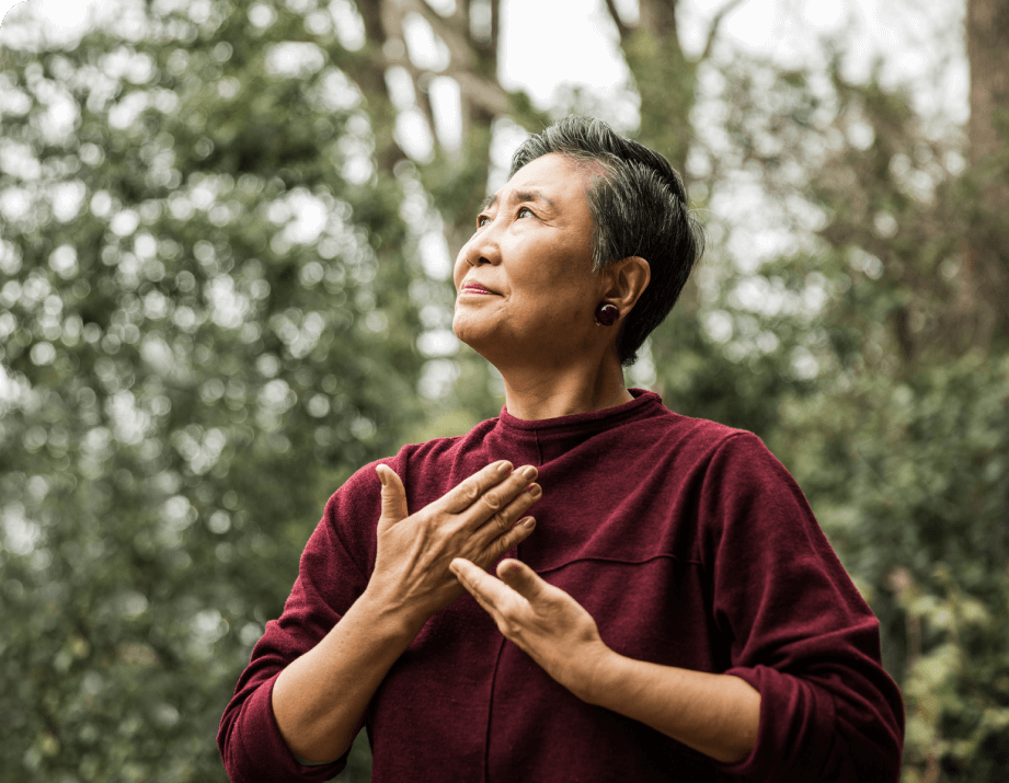 Senior woman doing tai chi outside, gazing gently upward