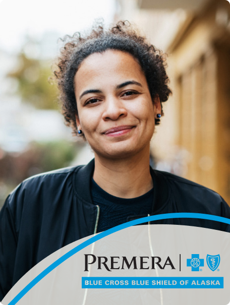 Woman with dark curly hair smiling at the camera and the Premera Blue Cross Blue Shield of Alaska logo in the bottom right
