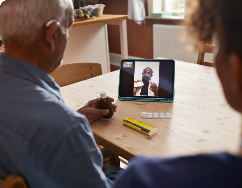 Older member and their partner reviewing medications with a provider on a tablet.