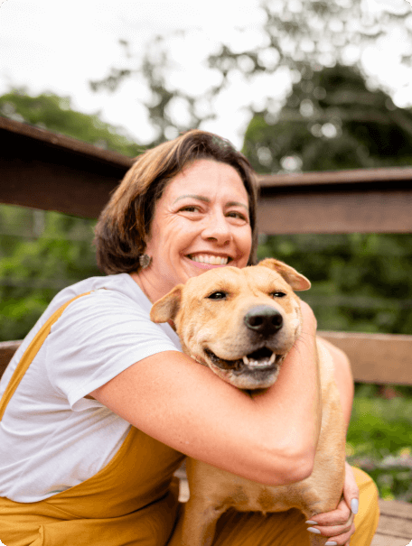 Smiling woman on her porch with her arms around her yellow dog, who also appears to be smiling Smiling woman on her porch with her arms around her yellow dog, who also appears to be smiling